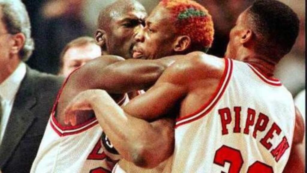 Dennis Rodman being held back by Michael Jordan and Scottie Pippen